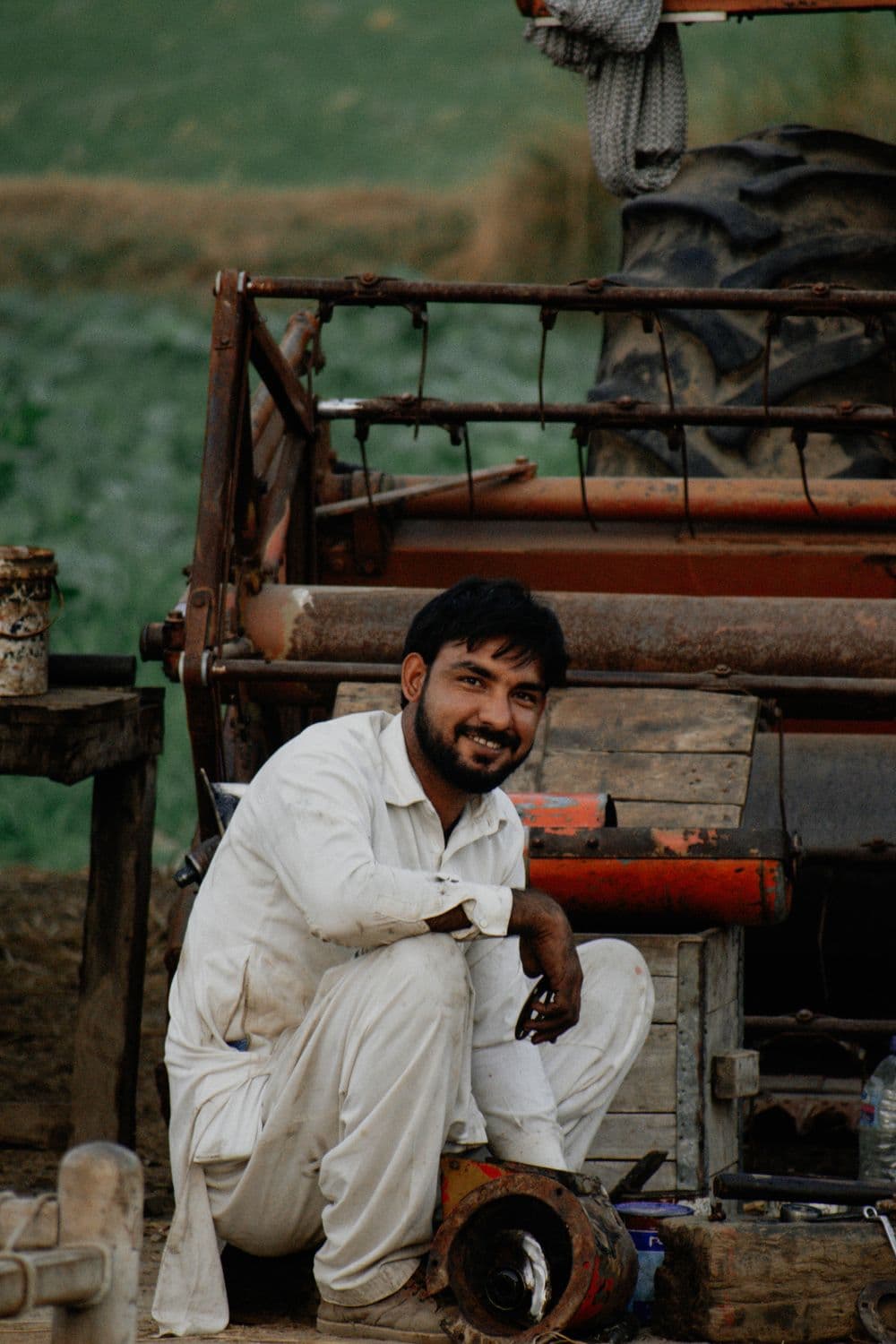 A mechanic with parts beside a harvester header